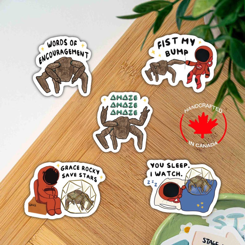 May include: Five vinyl stickers featuring brown, multi-legged alien creatures and red-suited astronauts. Text includes "WORDS OF ENCOURAGEMENT," "FIST MY BUMP," "AMAZE," "GRACE ROCKY SAVE STARS," and "YOU SLEEP. I WATCH." Designs include stars and geometric shapes.