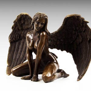 Puede incluir: Una escultura de bronce de una figura alada arrodillada con las alas extendidas. La figura est&aacute; desnuda y tiene una apariencia detallada y realista.