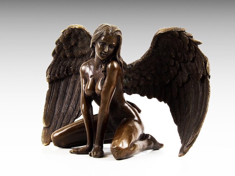Puede incluir: Una escultura de bronce de una figura alada arrodillada con las alas extendidas. La figura est&aacute; desnuda y tiene una apariencia detallada y realista.