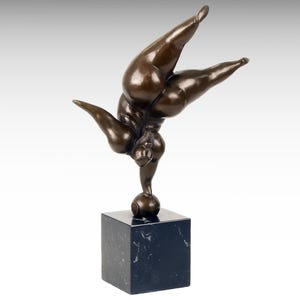 Könnte beinhalten: Bronzeskulptur einer Person, die auf einer Kugel balanciert. Die Skulptur steht auf einem schwarzen Marmorsockel.
