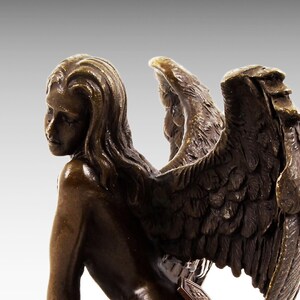 Puede incluir: Escultura de bronce de una mujer con alas. La mujer est&aacute; desnuda y tiene el pelo largo y suelto. Sus alas son grandes y detalladas, con plumas esculpidas en un estilo realista.