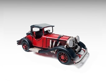 May include: A vintage-style red and black metal model car featuring a prominent front grille, silver-toned headlights, exposed side exhaust pipes, a black roof, and red wheels with black fenders. The vehicle has a detailed open cockpit interior.