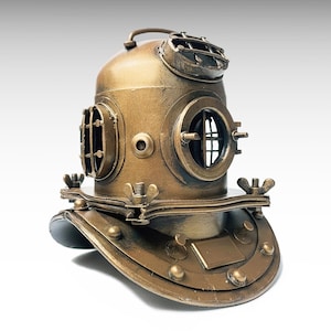 May include: A metallic bronze-colored vintage-style deep-sea diving helmet featuring a rounded dome, three circular porthole windows with protective metal grilles, a top handle, and a wide base plate secured with wing nuts and rivets.