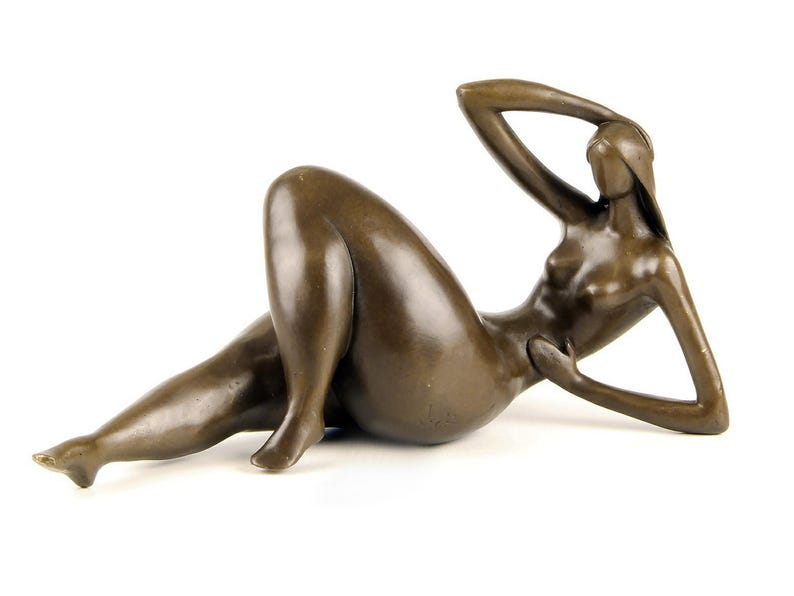May include: A bronze sculpture of a reclining nude figure. The figure is stylized and abstract, with long, flowing lines. The sculpture is in a relaxed pose, with one arm resting on the head and the other arm resting on the stomach.
