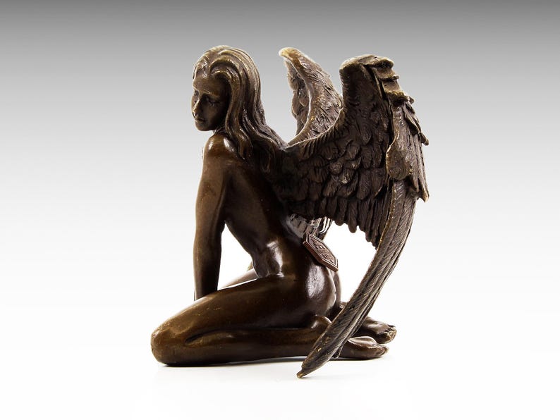 Puede incluir: Una escultura de bronce de un &aacute;ngel arrodillado con alas. El &aacute;ngel est&aacute; desnudo y tiene el pelo largo. Las alas son detalladas y se extienden detr&aacute;s del &aacute;ngel.