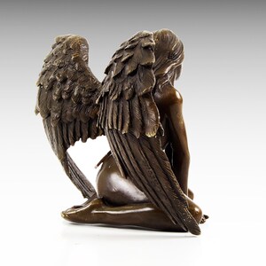 Puede incluir: Una escultura de bronce de un &aacute;ngel con las alas extendidas detr&aacute;s de &eacute;l. El &aacute;ngel est&aacute; arrodillado con la cabeza inclinada. La escultura est&aacute; hecha de bronce marr&oacute;n oscuro y tiene un acabado realista.