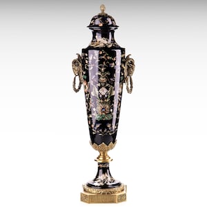 Pode incluir: Um vaso decorativo preto e dourado com desenhos florais intrincados e uma tampa. O vaso é decorado com madrepérola e outras pedras preciosas.
