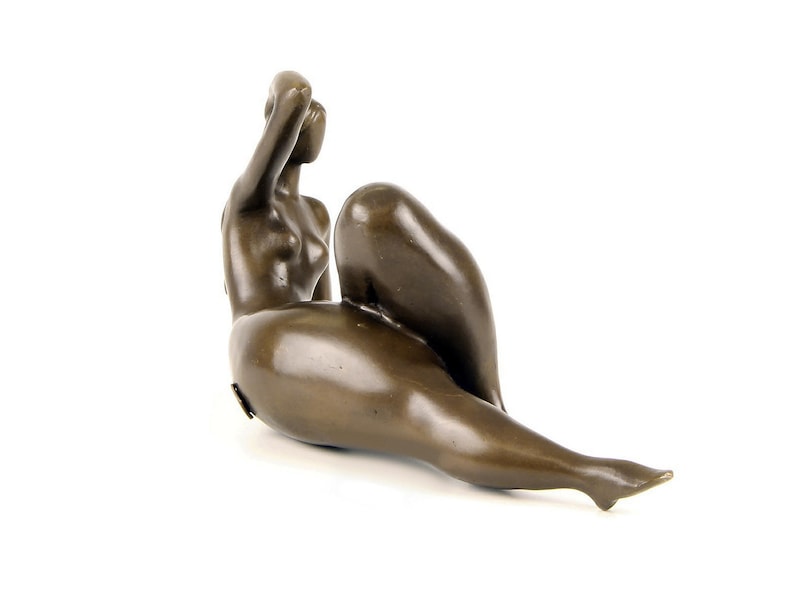 May include: A bronze sculpture of a nude figure in a reclining pose. The figure has a smooth, polished finish and is depicted with a relaxed, graceful form.