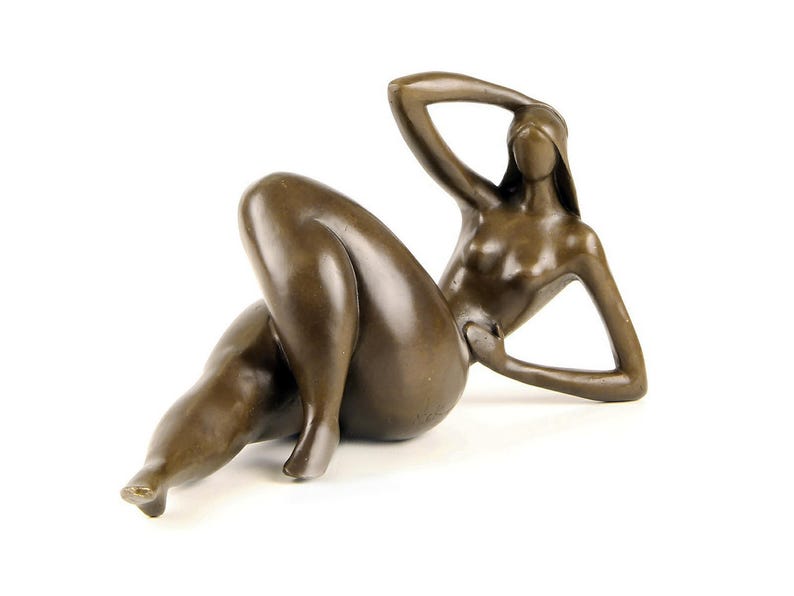 May include: A bronze sculpture of a nude figure reclining with one arm raised above their head. The figure is stylized and abstract, with smooth, rounded forms.
