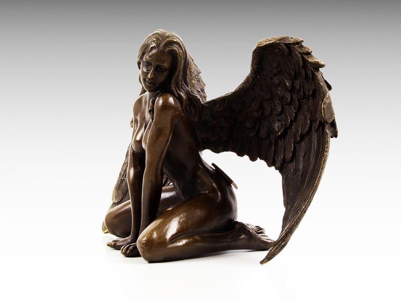 Puede incluir: Escultura de bronce de una mujer con alas. Est&aacute; arrodillada con la cabeza inclinada hacia abajo y las alas extendidas detr&aacute;s de ella.