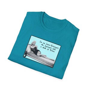 Può includere: Una maglietta turchese con un'immagine in bianco e nero di una donna su un divano. Il testo sull'immagine recita "I'm an Intro-Extrovert. An Introvert with a dash of Extra."