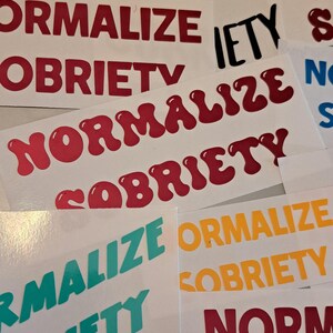 May include: A collection of stickers with the phrase "Normalize Sobriety" in various colors and fonts. The stickers are on a white background.