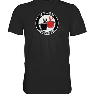 Puede incluir: Camiseta negra con un gráfico circular blanco que presenta una langosta y un cangrejo en ollas. El texto "Eat the Rich" y "Lecker Aktion" están dentro del círculo.