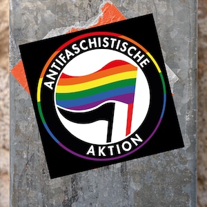 Könnte beinhalten: Ein schwarz-weißer Aufkleber mit einer Regenbogenflagge und dem Text "Antifa Schistische Aktion".