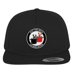 Op de afbeelding: Zwarte en witte flat brim baseballcap met een wit cirkelvormig logo met de tekst "Eat the Rich" met een kreeft en een pan in het midden en "Leckere Aktion" onderaan.