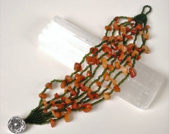 Large multi strand orange agate chip boho style bracelet with dark green seed beads and silver celtic knot button