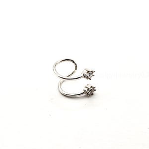 May include: A silver-colored, spiral-shaped ear cuff with two square, clear gemstones. The ear cuff is made of a shiny metal and is designed to wrap around the ear. The jewelry is set against a white background.