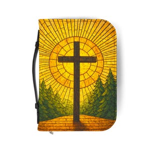 May include: A zippered case featuring a cross design. The image shows a brown cross set against a stained-glass style background of a sunburst, with green trees on either side. The case has a black handle.
