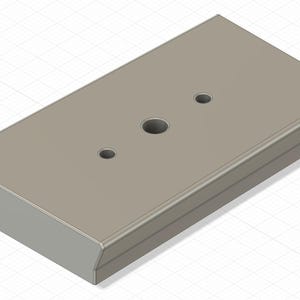 Puede incluir: Un objeto rectangular gris claro con bordes redondeados y tres agujeros circulares. El objeto parece estar hecho de un material sólido y se ve desde un ángulo ligeramente elevado. La superficie es lisa y de color uniforme.