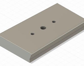Puede incluir: Un objeto rectangular gris claro con bordes redondeados y tres agujeros circulares. El objeto parece estar hecho de un material sólido y se ve desde un ángulo ligeramente elevado. La superficie es lisa y de color uniforme.