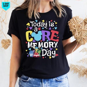 May include: Black t-shirt featuring a colourful graphic that reads "Today is a CORE MEMORY Day" with a Mickey Mouse head and characters from the film Inside Out.