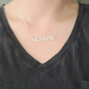 Puede incluir: Un collar de plata con tres colgantes de elefante. Los elefantes est&aacute;n conectados entre s&iacute; y miran en la misma direcci&oacute;n.