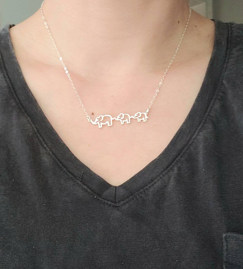 Puede incluir: Un collar de plata con tres colgantes de elefante. Los elefantes est&aacute;n conectados entre s&iacute; y miran en la misma direcci&oacute;n.