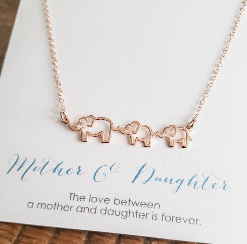 Puede incluir: Collar de oro rosa con tres siluetas de elefantes conectadas. El collar viene con una tarjeta que dice "Madre e Hija. El amor entre una madre y una hija es para siempre."