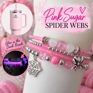 May include: A set of three beaded bracelets featuring pink matte beads, silver-toned spacers, clear crackle beads, and silver spider and spiderweb charms. The text Pink Sugar SPIDER WEBS is visible, along with a pink Stanley tumbler and a glow-in-the-dark view.