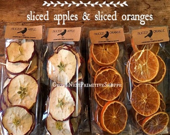 May include: Two clear plastic bags filled with dried fruit slices. One bag contains red and white apple slices, the other contains orange slices. The bags are labeled "Sliced Apple" and "Sliced Orange".