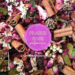 May include: A close-up of a purple and white potpourri mix with cinnamon sticks, dried rose petals, and other natural elements. The text "Prairie Rose potpourri" is written on a purple circle.