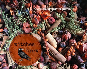 May include: A fall-themed arrangement featuring cinnamon sticks, small pumpkins, and dried botanicals in shades of orange, brown, and green. A circular label with the text "witches brew" and a crow illustration is in the foreground.