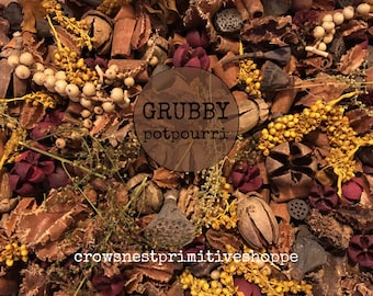 May include: A close-up of a brown and yellow potpourri mix with a variety of natural elements, including dried flowers, leaves, and bark. The text "GRUBBY potpourri" is visible in the center of the image.