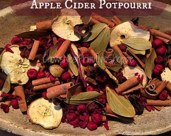 May include: Apple Cider Potpourri in a wooden bowl featuring dried apple slices, cinnamon sticks, green bay leaves, and small deep red berries. The text Apple Cider Potpourri is displayed at the top, with CrowsNestPrimitiveShoppe written below.