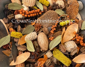 May include: A bowl filled with a variety of natural materials, including dried leaves, pods, and flowers. The materials are in shades of brown, yellow, and orange. The text "CrowsNestPrimitiveShoppe" is visible in the center of the image.