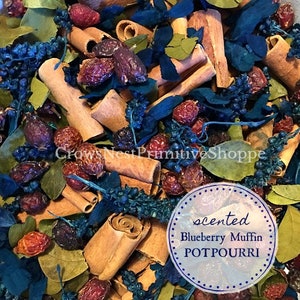May include: A close-up of a potpourri mix with cinnamon sticks, dried berries, and blue and green foliage. The label reads "scented Blueberry Muffin POTPOURRI".