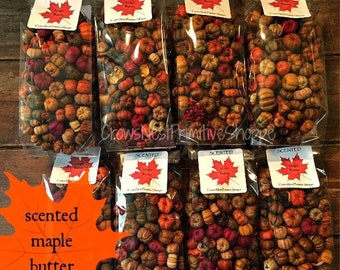 May include: Eight clear plastic bags filled with small, dried decorative pumpkins in shades of orange, red, brown, and yellow. Each bag features a white label with a red maple leaf graphic and the text Scented Maple Butter CrowsNestPrimitiveShoppe.