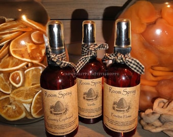 May include: Three brown glass bottles with spray tops and brown paper labels. The labels have the text "Room Spray" and different scents: "Country Cupboard", "Vanilla", and "Primitive Home".