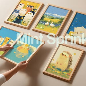May include: Five framed rectangular wall art prints featuring colorful illustrations of owls, ducks in a field, a polar bear, a group of llamas, a capybara in water, and a hedgehog, all enclosed in light-colored wooden frames with the text Mint Sprinkle.
