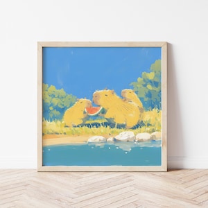 May include: A square framed art print featuring a digital illustration of three golden-yellow capybaras sitting by a blue river. One capybara holds a slice of red watermelon. The scene includes green foliage, white rocks, and a bright blue sky.