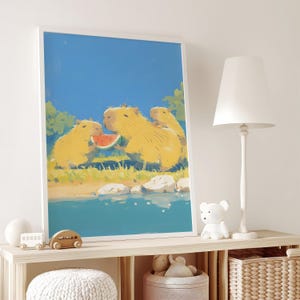 May include: A framed wall art print featuring a digital illustration of three yellow capybaras sitting by a blue body of water. The capybaras are eating a slice of red watermelon. The scene includes green foliage and white rocks under a clear blue sky.