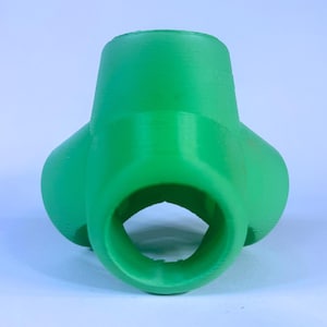 May include: A green plastic 3D printed object with three holes. The object is shaped like a sphere with a hole in the center.