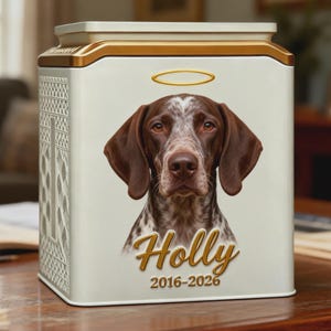 May include: A square white metal memorial urn featuring a portrait of a brown and white spotted dog with a gold halo above its head. The name Holly is printed in gold script below the dog, followed by the years 2016-2026 in gold text.