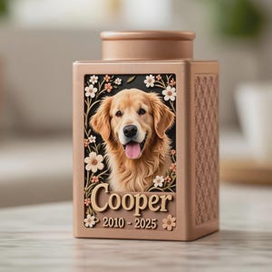 May include: A tan pet urn with a portrait of a Golden Retriever, framed by white flowers and greenery. The name "Cooper" and the years "2010-2025" are displayed below the portrait. The urn has a textured pattern on the sides.