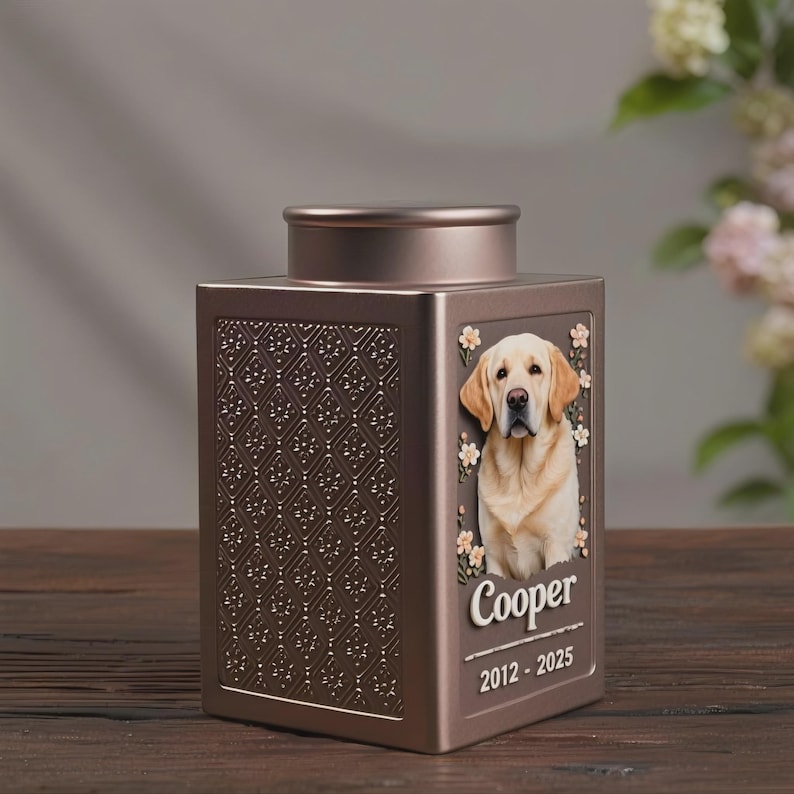 Peut inclure: Urne fun&eacute;raire pour animaux de compagnie de couleur bronze, de forme carr&eacute;e, avec un motif floral d&eacute;coratif sur un c&ocirc;t&eacute;. L'autre c&ocirc;t&eacute; pr&eacute;sente un portrait d'un Labrador Retriever jaune, le nom "Cooper" et les ann&eacute;es "2012-2025".