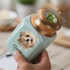 May include: A light blue ceramic pet urn, 4.72 inches high and 2.60 inches wide, with a gold-colored lid. The urn features a portrait of a dog named Charlie, with the year 2012 below the name. The lid has a floral design.