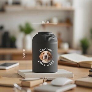 以下が含まれることがあります： ビーグルの写真、名前「Cooper」、日付「2011-2025」がプリントされた黒いペット用骨壺。骨壺の高さは15.09cm、幅は9.70cmです。白い正方形の台座の上に置かれています。