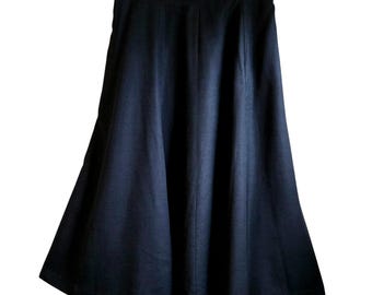 May include: A solid black midi-length skirt with a high-waisted design and a flared, A-line silhouette. The skirt features a clean, structured waistband and vertical seam detailing that runs down the front, creating a smooth, flowing drape.