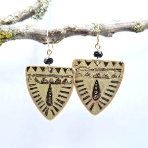 May include: A pair of gold-tone earrings with black geometric designs and black beads hanging from the bottom.