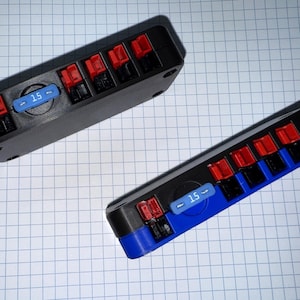 May include: Two black electrical terminal blocks with red and black connectors. Each block has a blue label with the number "15" on it. One block has a blue end, the other does not.